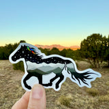 Horse-shaped sticker with a scenic design held in front of a natural landscape.  Waterproof vinyl sticker, Horse sticker, Vinyl decal, Laptop sticker, Water bottle sticker, Horse silhouette art, Die-cut sticker, Celestial sticker, Wildlife sticker, horse silhouette sticker, mountain sticker, feather sticker, watercolor feather sticker