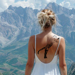 Woman with a tattoo of a panther on her back, standing against a mountainous landscape. tattoo certificate, tattoo permission slip, tattoo permission ticket, tattoo permission, tattoo stencil, tattoo flash, tattoo print, tattoo art, commission tattoo, custom tattoo, personalized tattoo